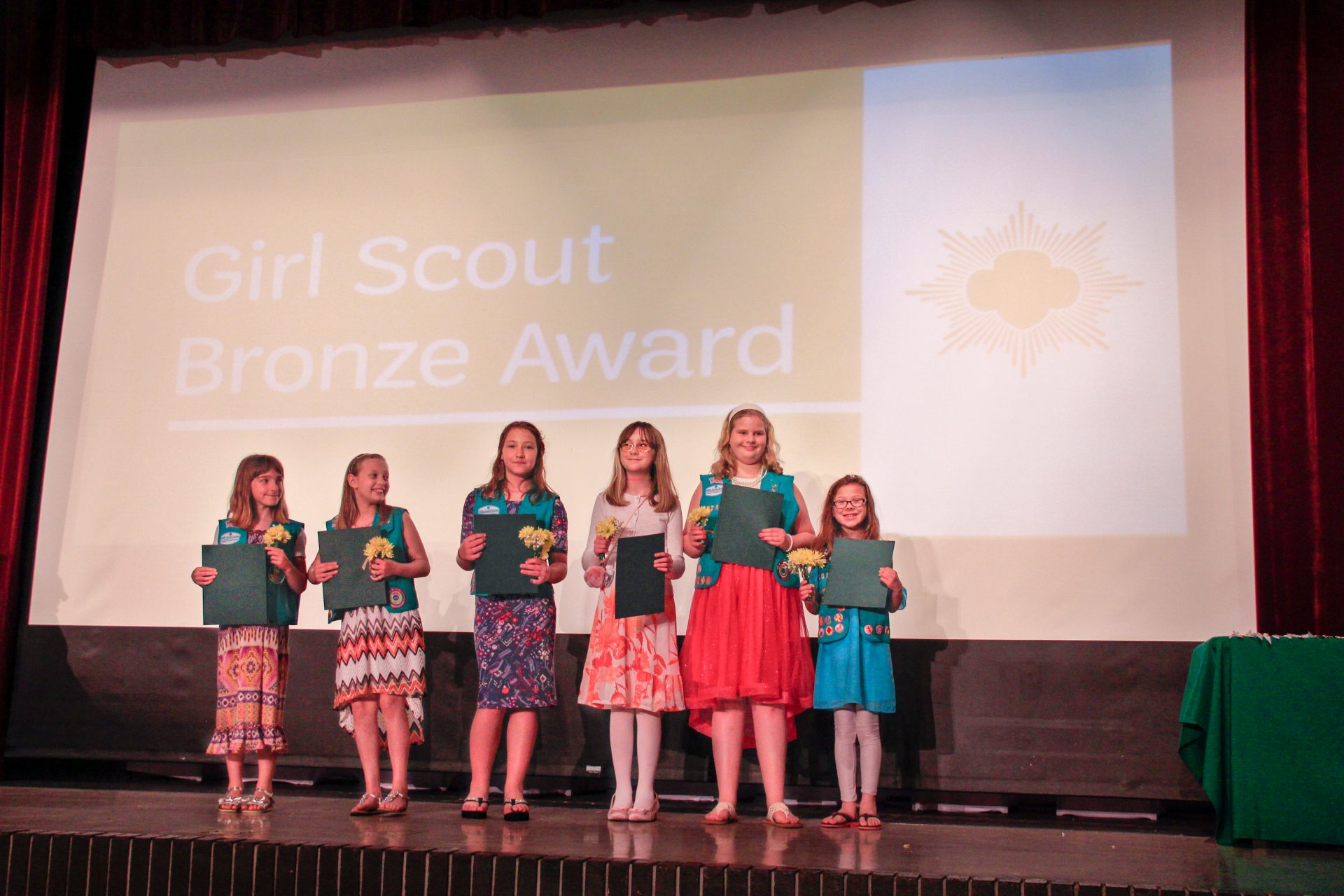  junior girl scout wearing uniform vest with bronze award pin 