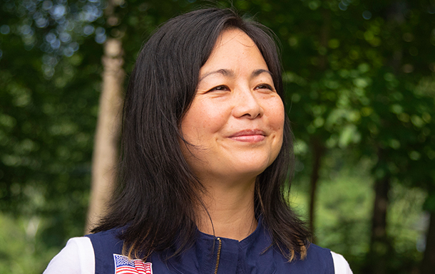 adult woman girl scout volunteer wearing vest outdoors smiling hiking