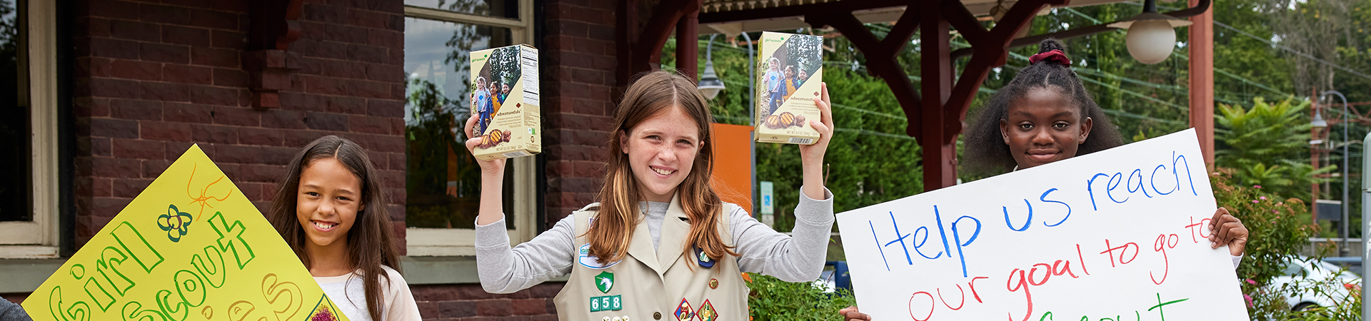  girl scout wearing uniform sash putting trefoil girl scout cookie boxes into cookie transport bag 