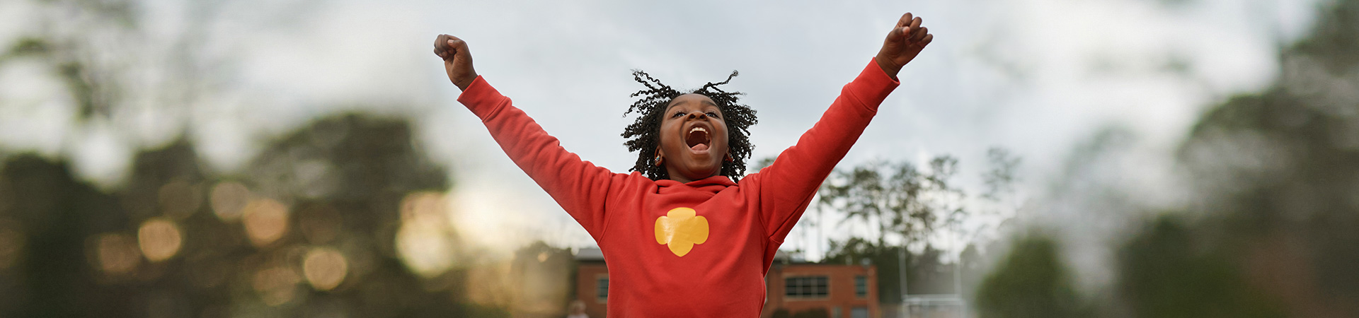  young girl scout outside cheering with hands in the air 